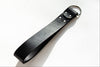 Black leather strap with metal ring on a white background