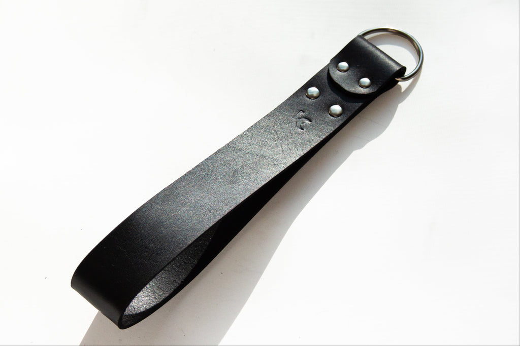 Black leather strap with metal ring on a white background